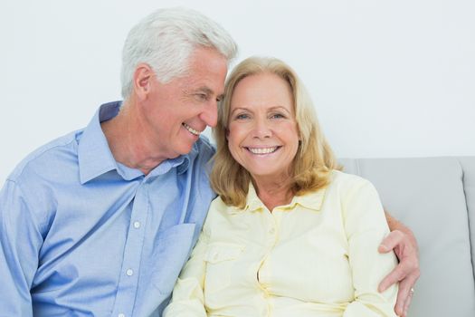 Happy romantic senior couple sitting on sofa in a house