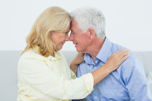 Romantic relaxed senior couple sitting on sofa in a house