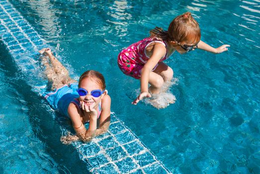 two happy little girls splashing around in the pool