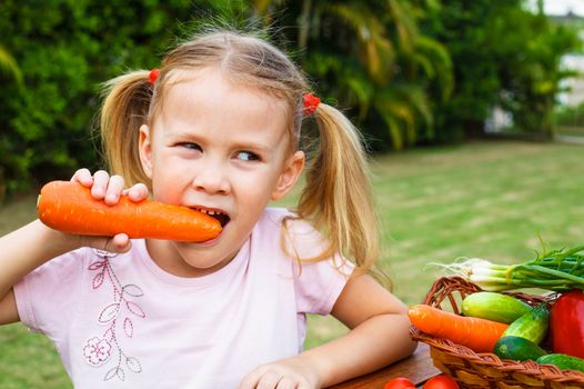 Happy little girl holding a carrots. Concept of healthy food.