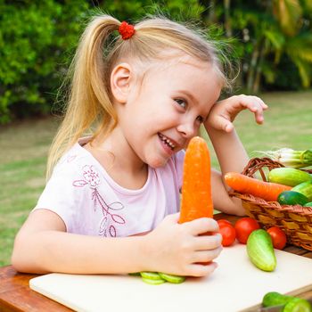 Happy little girl holding a carrots. Concept of healthy food.