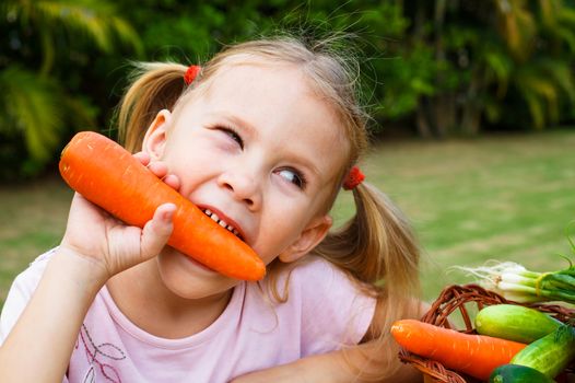 Happy little girl holding a carrots. Concept of healthy food.