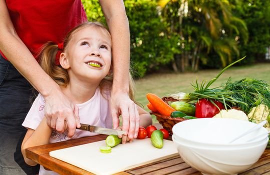 mother teaches daughter  knife cut cucumber