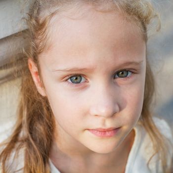 sad little girl on the background of an white wall