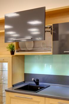 Fragment of the kitchen interior. Open hinged kitchen cabinet with utensils.