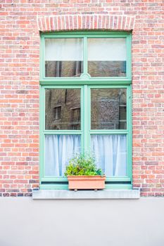 green painted wood arched window in a red brick wall Bruges
