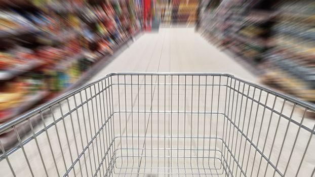 Shopping cart and motion blur in supermarket aisle