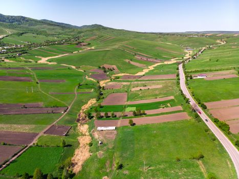 Rural panorama, aerial view: cultivated lands, houses and forest from above
