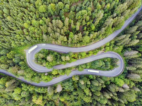 Above view of winding mountain pass road through green forest, Romania