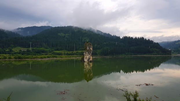 Rock and lake, surrounded by the forest, summer landscape in Romania