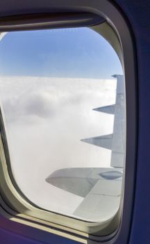 Sky and clouds from plane window, with focus on window