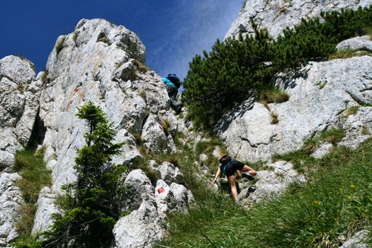 Teens climbing on the rocks in alpine area of Piatra Craiului mountains, Romania