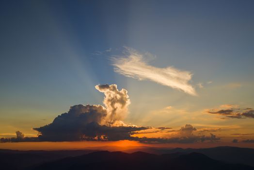 Orange sunset, sun rays breaking the clouds