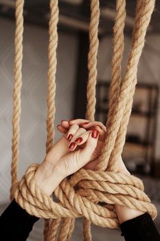 Tied with a rope female hands. Beautiful hands with red nails. Concept of sex or violence