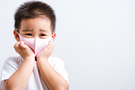 Portrait Asian little child boy wearing cloth face mask protective filter dust pm2.5, COVID-19 or coronavirus concept he looking to camera, studio shot isolated on white background with copy space