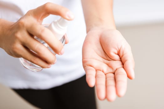 Closeup Hand Asian young woman applying spray pump dispenser sanitizer alcohol on hand wash cleaning, hygiene prevention COVID-19 or coronavirus protection concept, isolated on white background