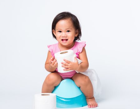 Asian little cute baby child girl education training to sitting on blue chamber pot or potty with toilet paper rolls, studio shot isolated on white background, wc toilet concept