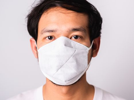 Closeup Asian handsome Man wearing surgical hygienic protective cloth face mask against coronavirus, studio shot isolated white background, COVID-19 medical concept