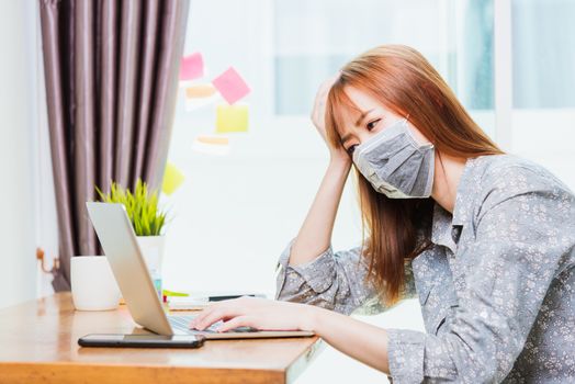 Work from home concept, Asian young business woman wearing face mask protective quarantines disease pandemic coronavirus or COVID-19 her working on desk with laptop computer at home office