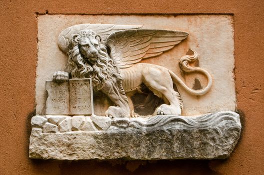Carved stone winged lion - the symbol of Venice - on the exterior wall of an historic building in the centre of the city.