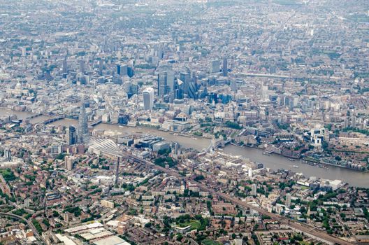Aerial view of Southwark and the City of London with the River Thames flowing under Tower Bridge and the tower blocks of the Shard, Gherkin and the Barbican visible.  View from the South East with the rail terminus of London Bridge Station towards the left hand side. 