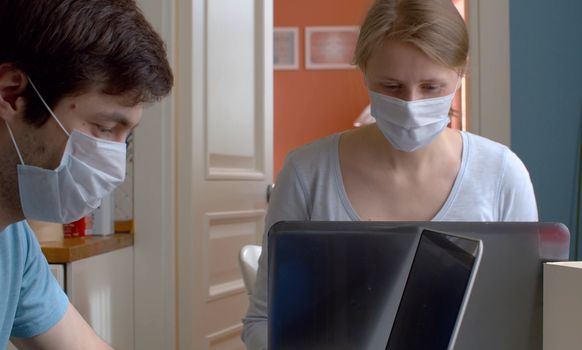 Nice couple working from home on computers in bright kitchen. Remote work during quarantine, coronavirus epidemic.