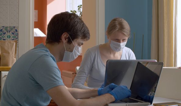 Nice couple working from home on computers in bright kitchen. Remote work during quarantine, coronavirus epidemic.