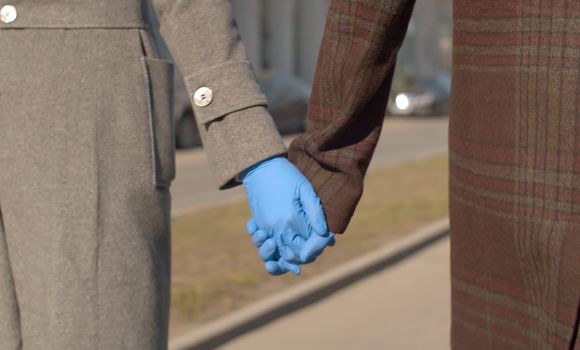 Close up hands of couple in blue latex gloves walking during coronavirus epidemic