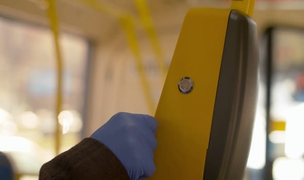 Close up hand in protective gloves paying in the bus. A man on a bus pays for fare with an electronic card using a validator. Coronavirus epidemic
