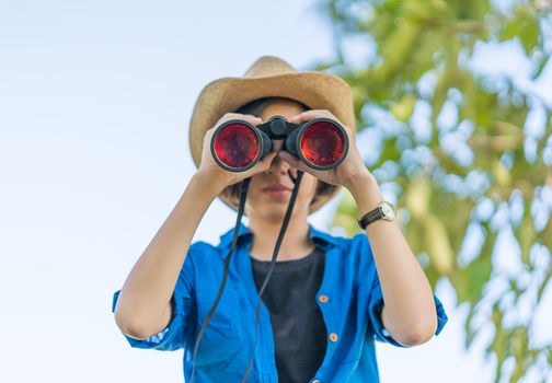 Close up Young asian woman short hair wear hat and hold binocular in grass field countryside Thailand