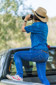 Close up Young asian woman short hair wear hat and hold binocular in grass field countryside Thailand