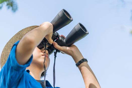 Close up Young asian woman short hair wear hat and hold binocular in grass field countryside Thailand