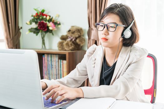 Teenage girl short hair in smart casual wear working on laptop while sit near window in home office