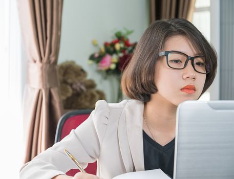 Teenage girl short hair in smart casual wear working on laptop while sit near window in home office