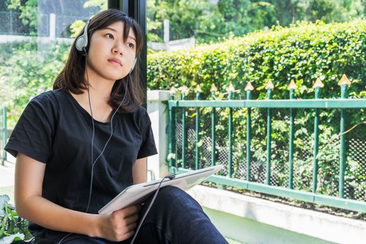 Happy teenage female  listening to the music from a digital tablet in room at home