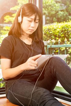 Happy teenage female  listening to the music from a digital tablet in room at home