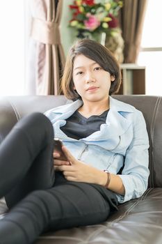 Close up young asian woman short hair use mobile phone on the couch in living room at home