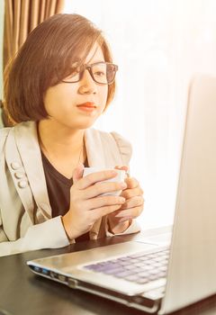 Woman teenage short hair in smart casual wear working on laptop while sit near window in home office