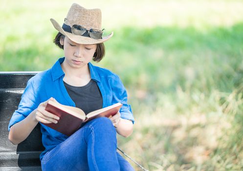 Young asian women short hair wear hat and sunglasses read a book ,sit on pickup truck in countryside Thailand