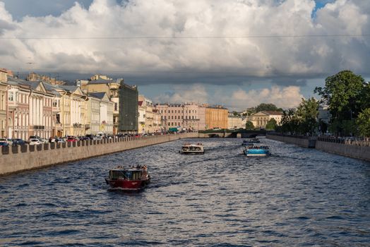 Snkt-Peterbrug, Russia - July 2, 2019:  Fontanka River embankment and pleasure sightseeing boats on the river in summer in St. Petersburg