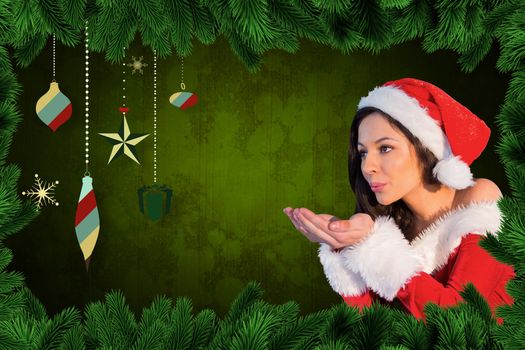 Pretty girl in santa outfit blowing against fir branches and christmas deocrations