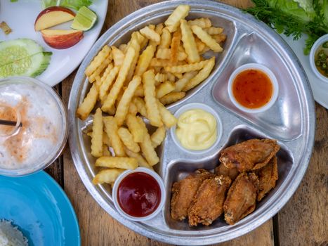 The fried chicken drumstick and french fries on wooden background.