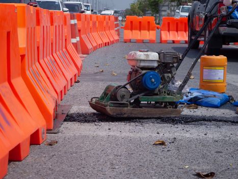 Worker use vibratory plate compactor compacting asphalt at road repair