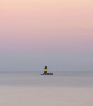 Lighthouse of Burela, Spain surrounded by the sea with silky effect and sky in pastel tones