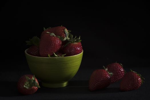 Strawberries in a green bamboo bowl on a black background