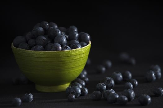 Blueberries in a green bamboo bowl on a black background