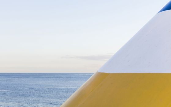 Geometry of a chimney of a cruise ship and the horizon of the sea, in yellow, blue and white