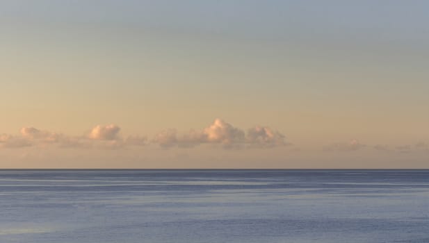 Sunset with a calm sea and small clouds on the horizon line