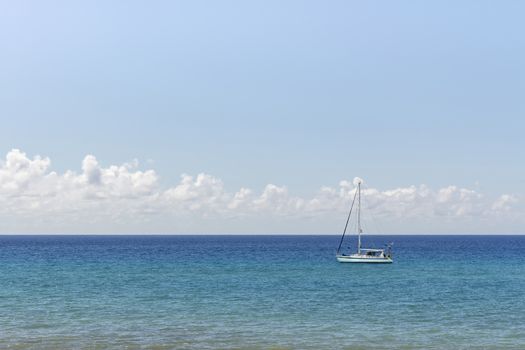 Minimalist seascape with a white boat on a turquoise waters and cloudy sky