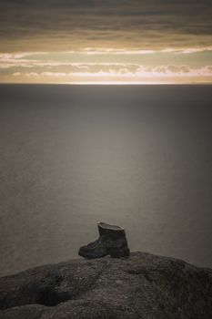 Sculpture of a bronze boot dedicated to the pilgrims of the Way of Saint James in Finisterre, Spain, at sunset